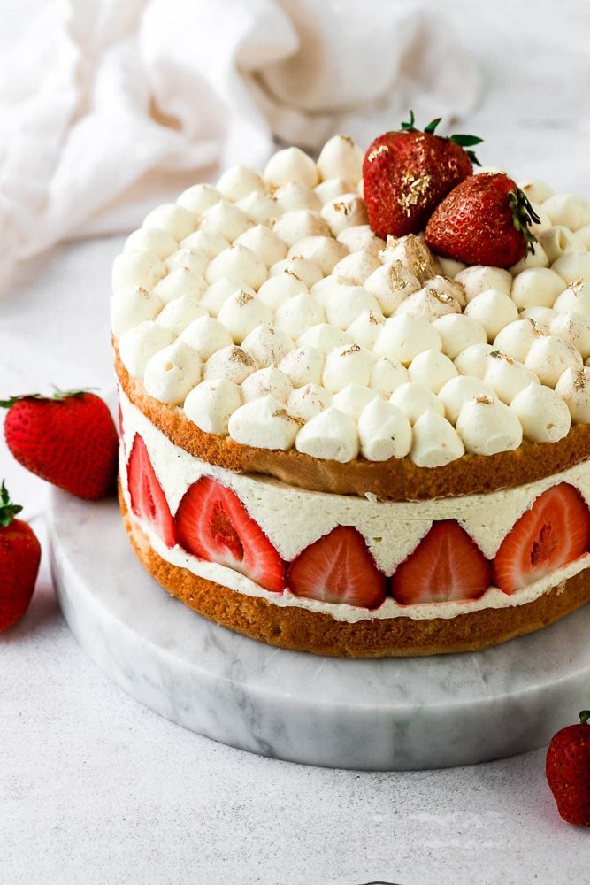 Strawberry fraisier cake topped with cream and fresh strawberries